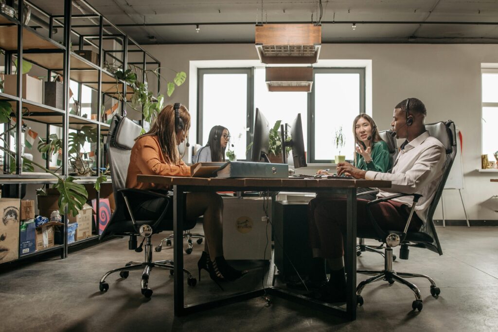 A diverse call center team working on computers with headsets in a modern office setting.