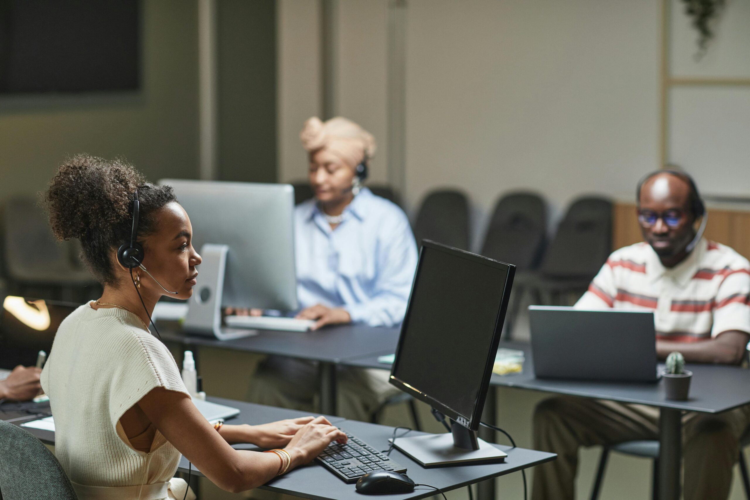 Three call center agents at work, focused and professional in a modern office environment.