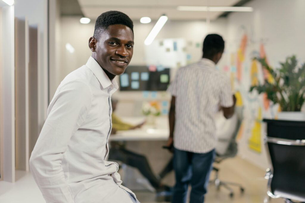 A smiling African American man in a modern office setting, embodying workplace positivity.