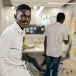A smiling African American man in a modern office setting, embodying workplace positivity.